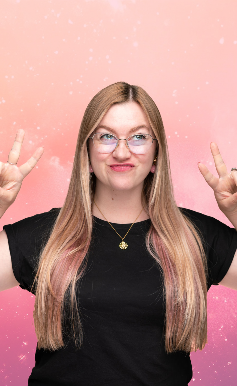 Pia Marlen Ungruh Soulful Branding & Design Junge Frau mit langen, blonden Haaren und Brille, zeigt das Peace-Zeichen vor einem rosa Hintergrund.